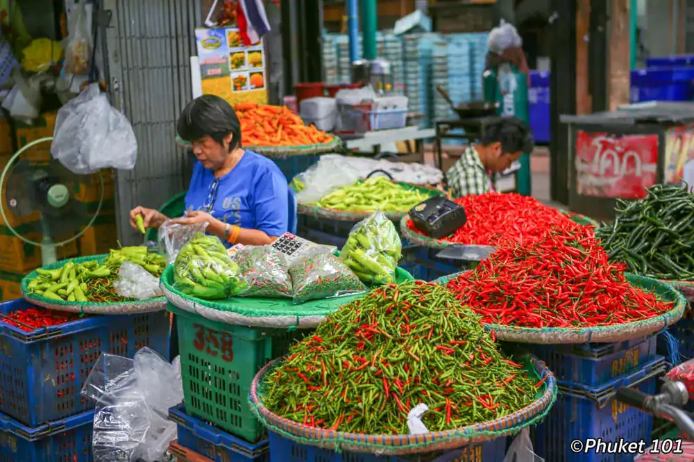 Local Phuket market with fresh Thai ingredients and vendors preparing produce